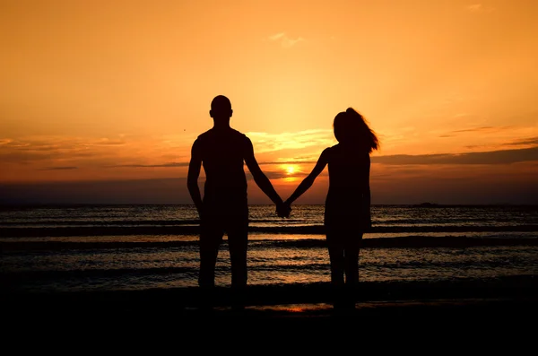 Casal desfrutando seu tempo no nascer do sol na praia — Fotografia de Stock