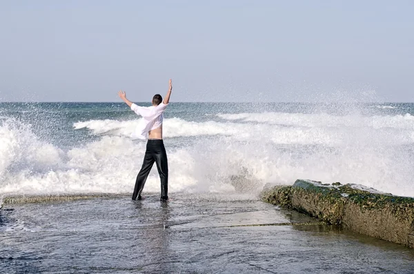 Молодой красивый бизнесмен наслаждается своим временем на пляже, пока волны ударяются о берег — стоковое фото