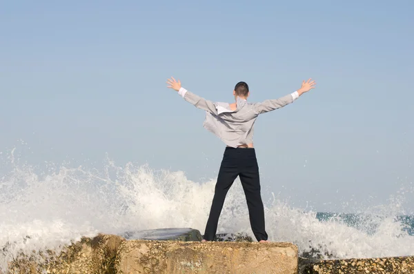 Young beautiful businessman enjoying his time on a beach while waves are hitting the shore — Stock Photo, Image