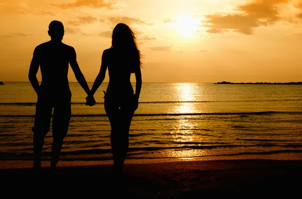 Pareja disfrutando de su tiempo al amanecer en la playa — Foto de Stock