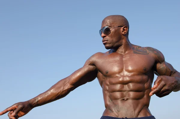 Strong bodybuilder man with perfect abs, shoulders,biceps, triceps and chest posing with sky as background — Stock Photo, Image