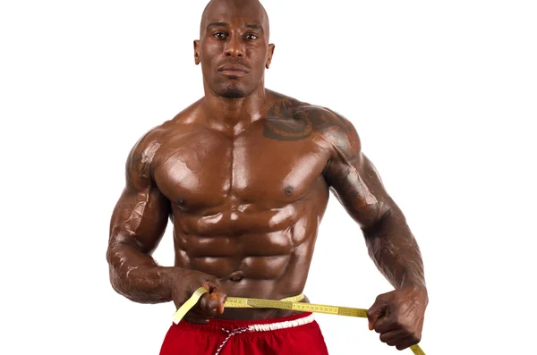 Black bodybuilder taking his muscle measurements with a centimeter. Strong man with perfect muscles. Isolated on white background — Stock Photo, Image