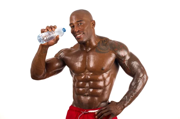 Zwarte bodybuilder drinking water na een harde training. sterke man met perfecte spieren. geïsoleerd op witte achtergrond. — Stockfoto