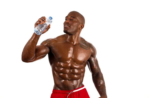 Bodybuilder noir boire de l'eau après une séance d'entraînement difficile. Homme fort avec des muscles parfaits. Isolé sur fond blanc . — Photo