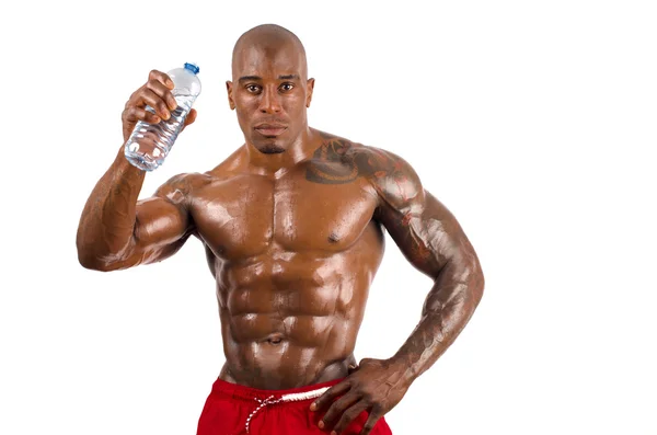 Black bodybuilder drinking water after a hard workout. Strong man with perfect muscles. Isolated on white background. — Stock Photo, Image