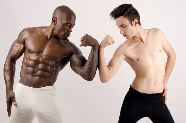 Hvid mager mand versus sort bodybuilder - Stock-foto