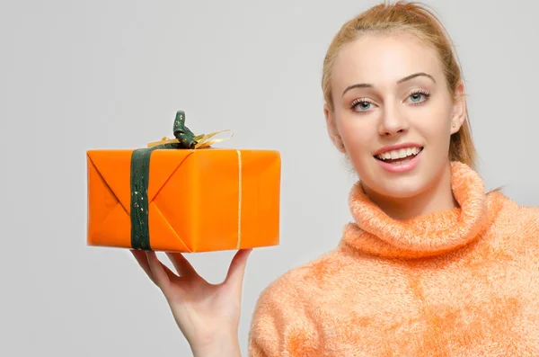 Mulher de cabelo ruivo bonita segurando um presente de Natal. Menina em laranja feliz com um presente . — Fotografia de Stock