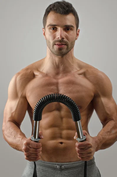 Bodybuilder utbildning med bendy bar. stark man med perfekta abs, Pécs axlar, biceps, triceps. isolerad på vit bakgrund — Stockfoto