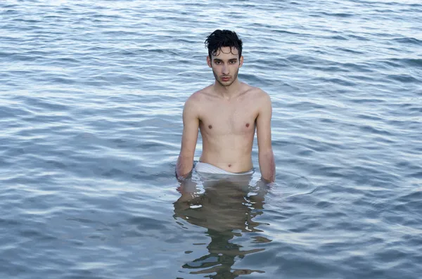 Beautiful young man in swimsuit relaxing in the sea during summer vacation — Stock Photo, Image