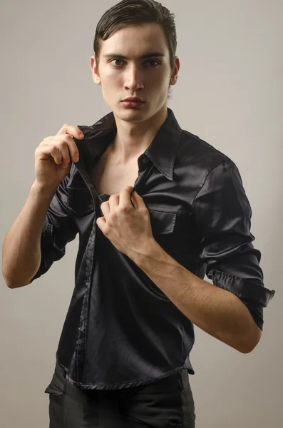 Sexy krásný mladý muž nosí černou košili a svlékání — Stock fotografie