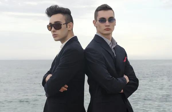 Twee jonge zakenman poseren mode op het strand en genieten van hun vakantie — Stockfoto