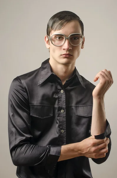 Hermoso joven vestido con una camisa negra y usando anteojos y pareciendo un friki — Foto de Stock