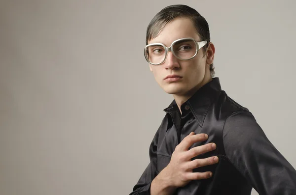 Hermoso joven vestido con una camisa negra y usando anteojos y pareciendo un friki — Foto de Stock