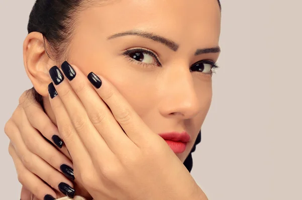 Profile of a brunette woman with red lips holding her hand on her face and showing her new manicure and black nails, beautiful perfect fingers — Stock Photo, Image