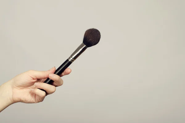 Cerca de una mano de mujer sosteniendo un cepillo de maquillaje — Foto de Stock