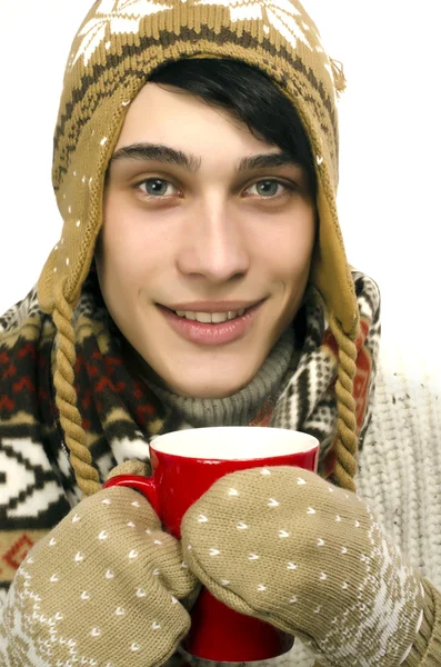 Portrait d'un bel homme portant un pull, des gants, une écharpe et un chapeau, habillé pour le froid hivernal et buvant une tasse de thé chaud — Photo