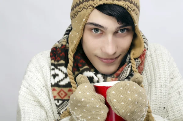 Retrato de um homem bonito vestindo suéter, luvas, cachecol e um chapéu, vestido para o inverno frio e beber uma xícara quente de chá — Fotografia de Stock