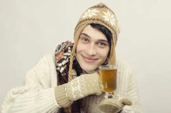 Портрет красивые мужчины носить свитер, перчатки, шарф и шляпу, одетый в зимнюю стужу и выпивать чашку горячего чая