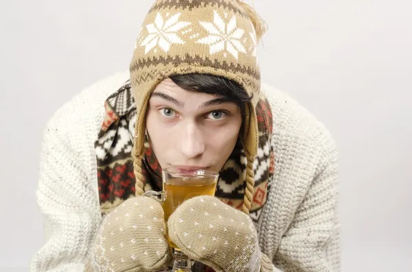 Retrato de un hermoso hombre con suéter, guantes, bufanda y sombrero, vestido para el frío invernal y bebiendo una taza de té caliente — Foto de Stock