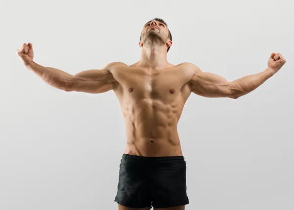 Forte fisiculturista homem com abdominais perfeitos, ombros, bíceps, tríceps e peito flexionando seus músculos Fotografia De Stock