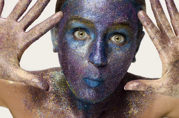 Mooi gezicht van een vrouw bedekt in glitter close up van een vrouw gezicht bedekt met blauw en paars glitter met plezier en beeing eng — Stockfoto