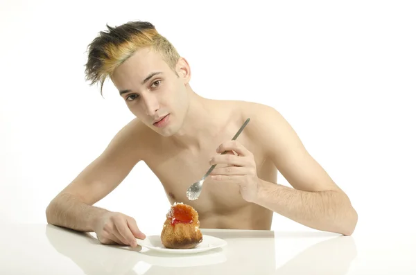 Hungry young man eating a cream cake, topless man tasting sweets — Stock Photo, Image