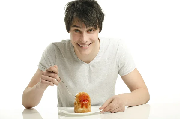 Jeune homme affamé mangeant un gâteau à la crème, homme dégustant des bonbons — Photo