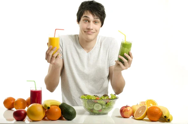 Homem feliz escolhendo entre suco de laranja e smoothie verde. Jovem alegre comendo salada saudável e frutas. Isolado em branco . — Fotografia de Stock