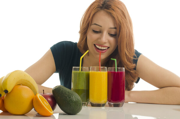 Happy woman holding in front of her three different smoothie.. Cheerful young woman eating healthy salad, fruits , orange juice and green smoothie