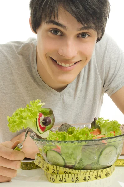 L'uomo misura i bicipiti con un centimetro mentre mangia insalata biologica sana per una dieta perfetta. Cibo verde per una vita sana — Foto Stock