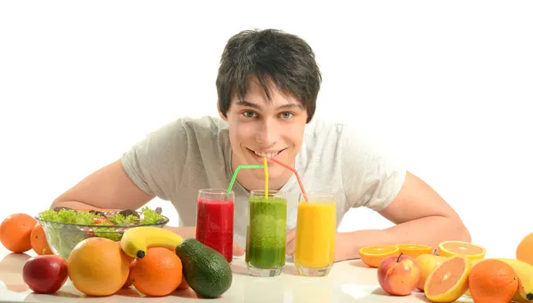 Gelukkig man met een tafel vol met biologisch voedsel, sappen en smoothie. vrolijke jonge man eten gezonde salade en fruit. geïsoleerd op wit. — Stockfoto