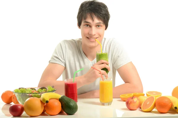 Szczęśliwy człowiek o stół pełne żywności ekologicznej, soki i koktajl. wesoły młody człowiek jedzenie zdrowe sałatki i owoce. na białym tle. — Zdjęcie stockowe