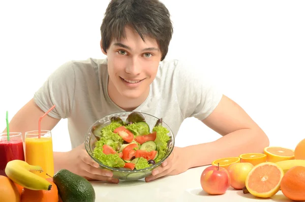 Lycklig att ha ett bord fullt av ekologiska livsmedel, juice och smoothie. glad ung man äta hälsosam sallad och frukt. isolerad på vit. — Stockfoto