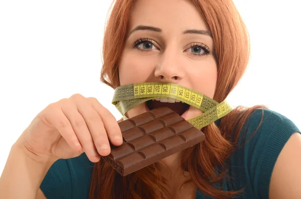 Happy woman eating a yummy chocolate and having some sugar for an active day during diet, with a centimeter on her mouth — Stock Photo, Image
