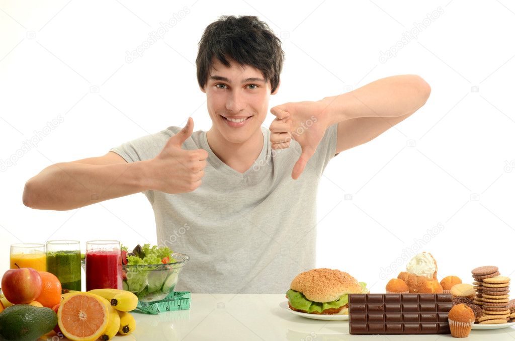 Man choosing between fruits, smoothie and organic healthy food against sweets, sugar, lots of candies and a big hamburger, unhealthy food