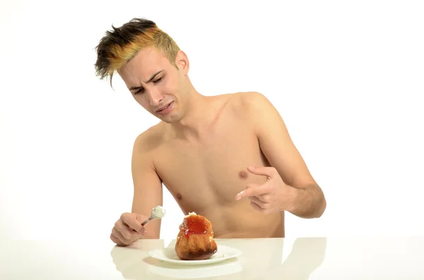 Hungry young man disgusted by the spoiled cream cake, topless man tasting sweets — Stock Photo, Image