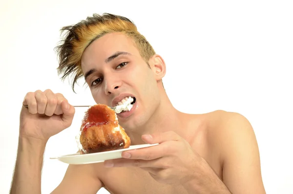 Hungry young man eating a cream cake, topless man tasting sweets — Stock Photo, Image