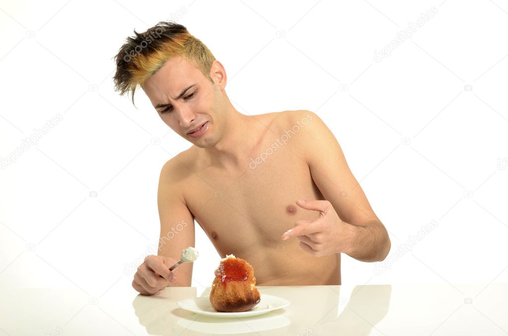 Hungry young man disgusted by the spoiled cream cake, topless man tasting sweets