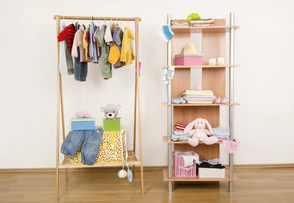 Dressing closet with clothes arranged on hangers.Wardrobe of newborn,kids, babies full of all shades of blue an orange clothes, shoes,accessories and toys — Stock Photo, Image