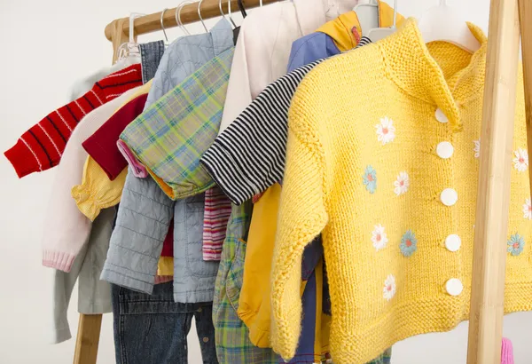 Armario de vestir con ropa dispuesta en hangers.Wardrobe de recién nacidos, niños, bebés llenos de todos los tonos de azul una ropa naranja, zapatos, accesorios y juguetes — Foto de Stock