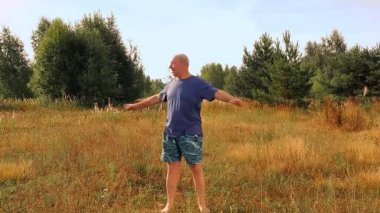 Orta yaşlı bir adam sabah çayırda fiziksel egzersiz yapar.