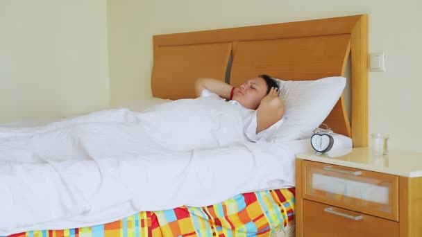 Una donna a letto si sveglia dal suono della sveglia la mattina presto, la spegne maledicendo e si addormenta coperta da una coperta — Video Stock