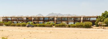 Çölün ortasında, arkasında dağlar olan evler inşa etmek. Yatay fotoğraf.