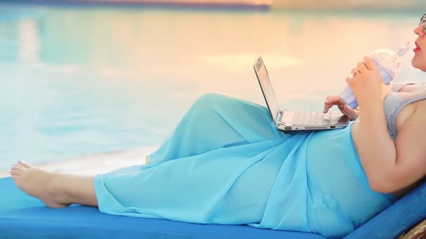 一位穿着泳衣 躺在游泳池边晒太阳的妇女的手在笔记本电脑上工作 没有脸的射击 中期计划 — 图库视频影像