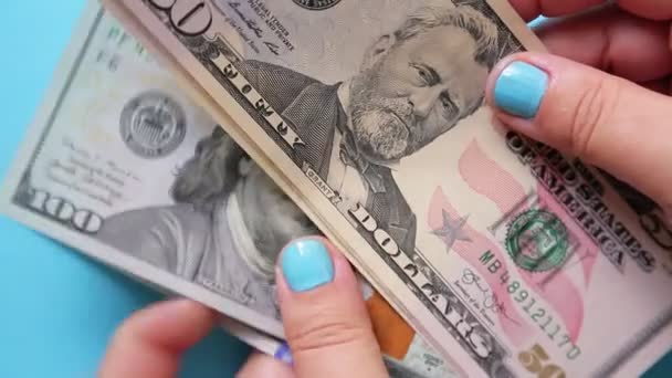 Mãos femininas contam notas de dólares num fundo azul. — Vídeo de Stock