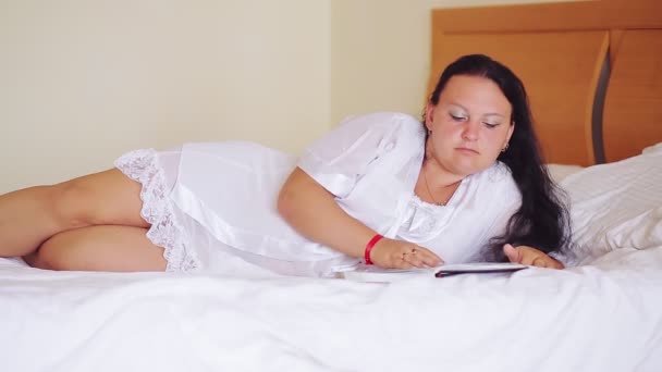 白い衣を着たユダヤ人女性が広いベッドの上で本を読んでいる — ストック動画