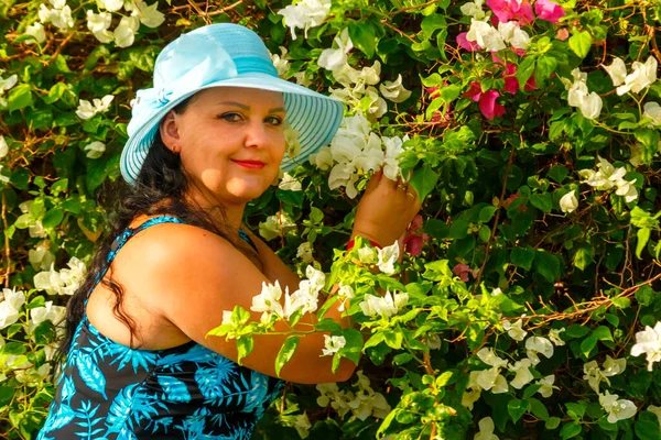 Mujer morena en sombrero entre buganvillas florecientes en un día soleado. —  Fotos de Stock