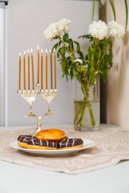 Herkesin donut ve bir vazo çiçeğin yanında olduğu aydınlık bir hanuka..