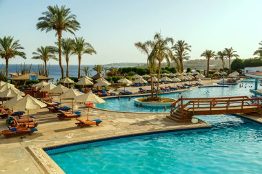 Lüks otelin yanında güneşli havuz ve şemsiyeler..