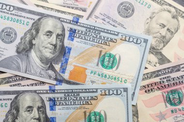 One hundred dollar bills are randomly arranged on a flat surface.